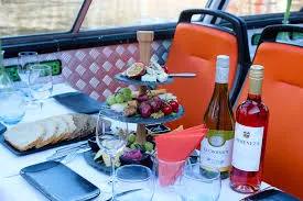 Close up of a cheese platter and wine glasses set on a table inside a canal boat.
