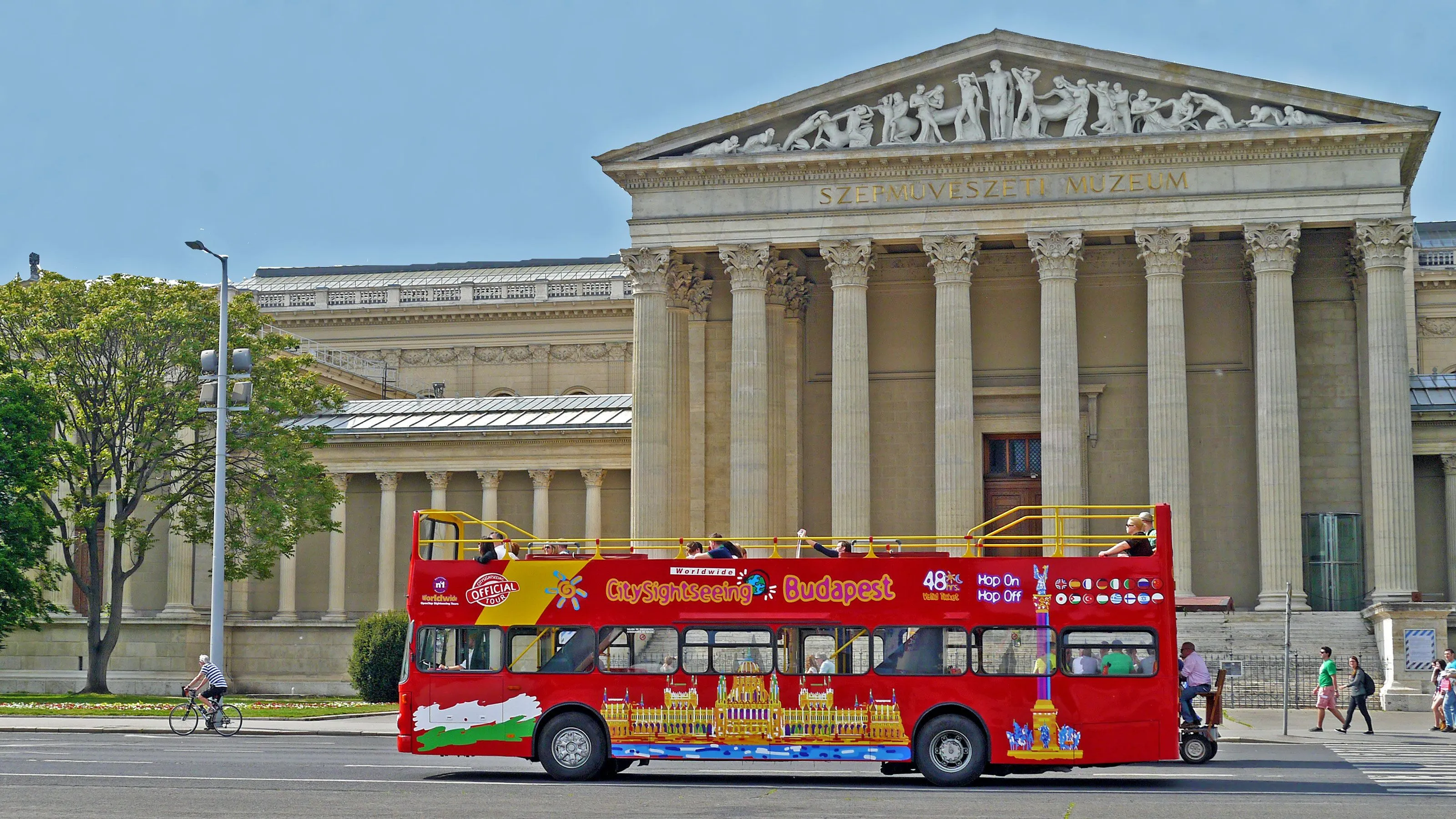 Open-top sightseeing bus passing landmarks in Budapest