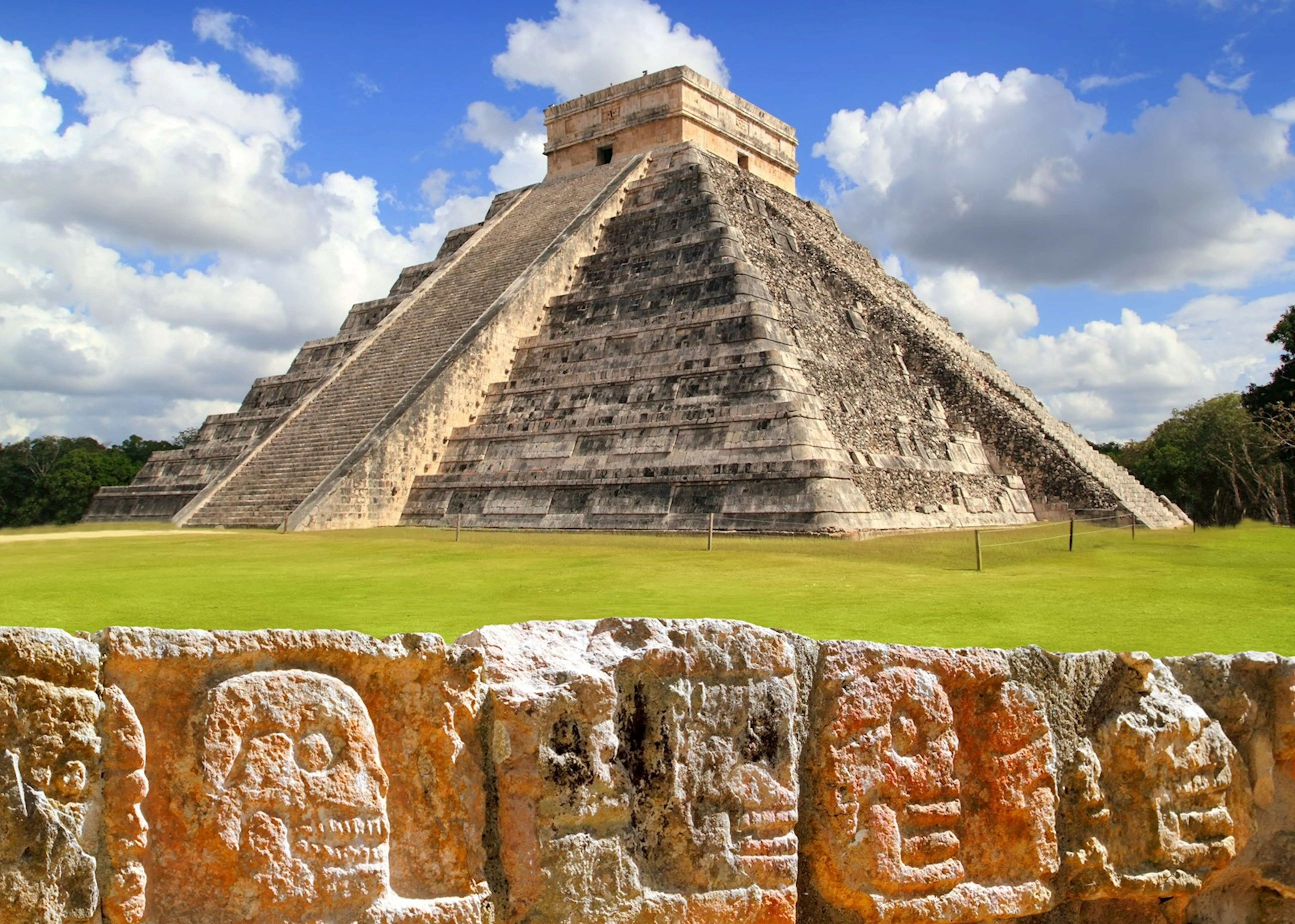 Travelers approaching the Kukulkan pyramid at Chichen Itza under clear daylight