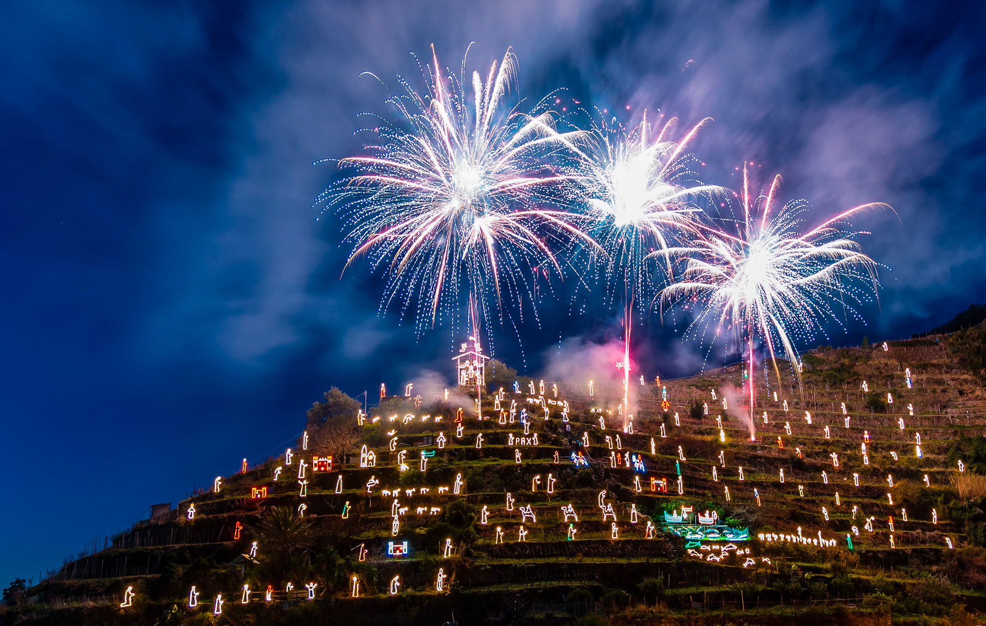 Illuminated nativity display on Manarola hillside during evening celebrations