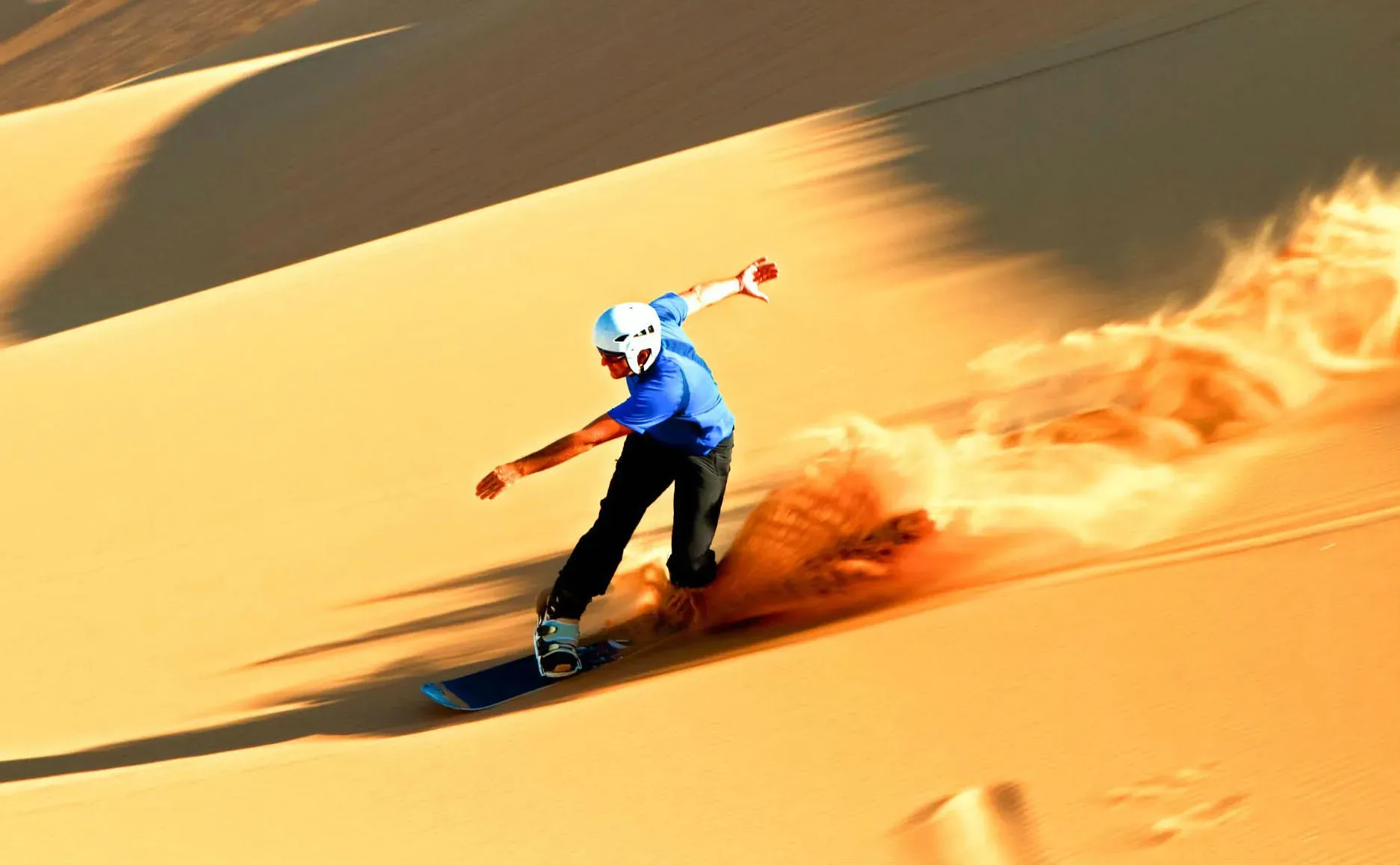Sandboarder carving down a dune in Dubai