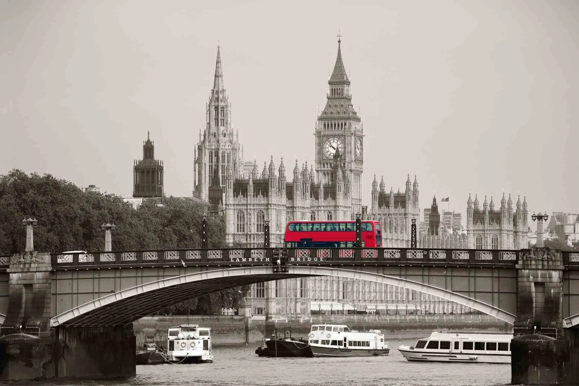 Iconic red bus passing Big Ben in monochrome with red accent