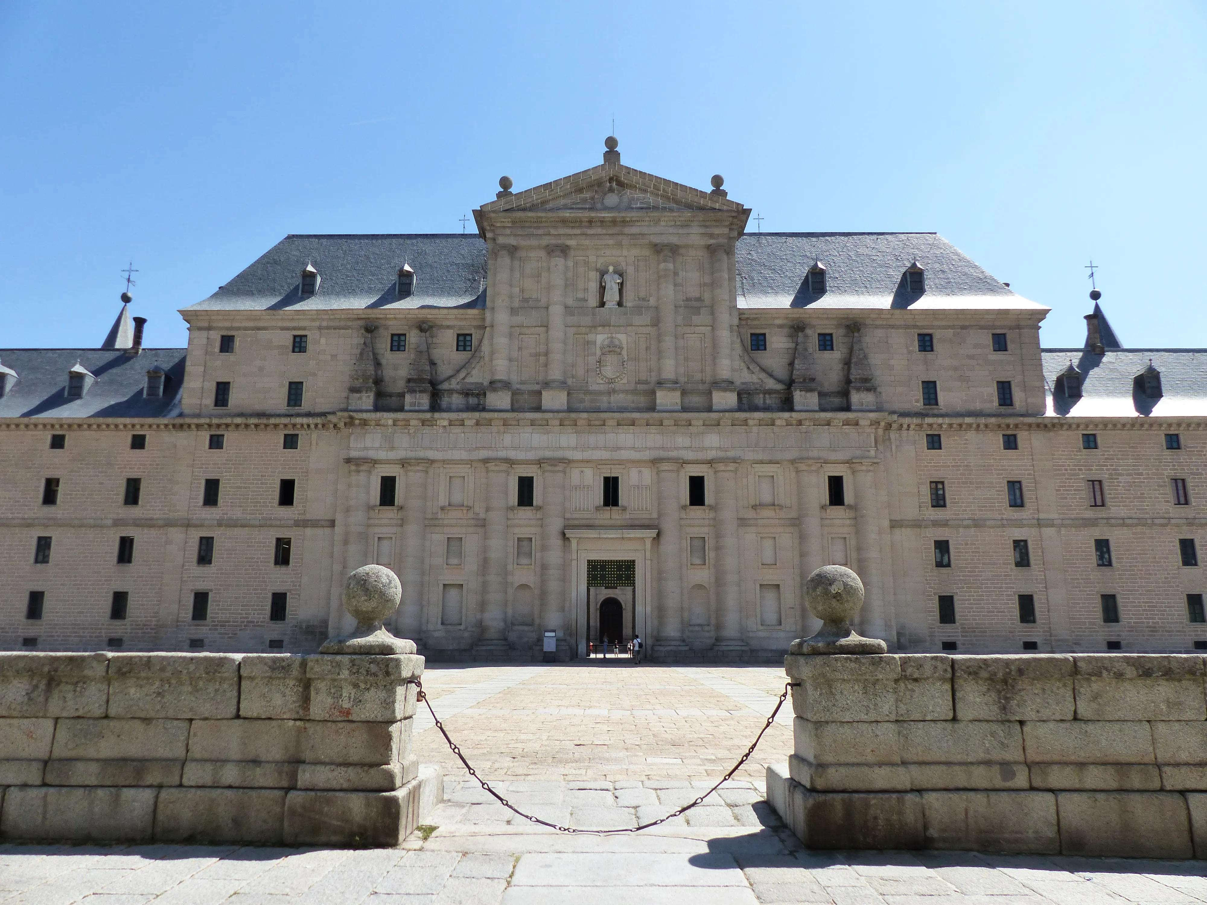 Sober Herrerian east facade of El Escorial under blue sky