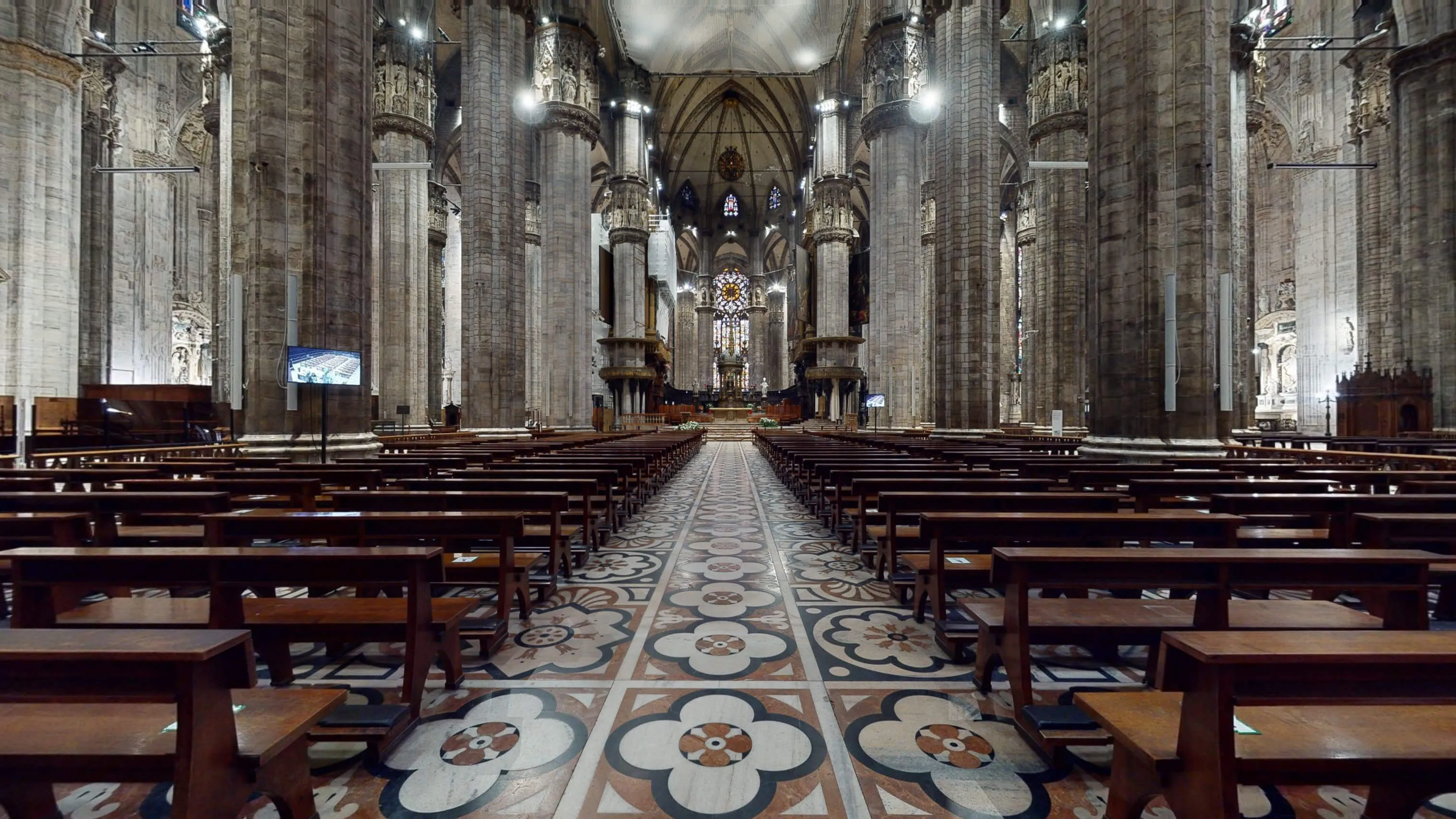 Interior nave of Milan Cathedral with light filtering through stained glass