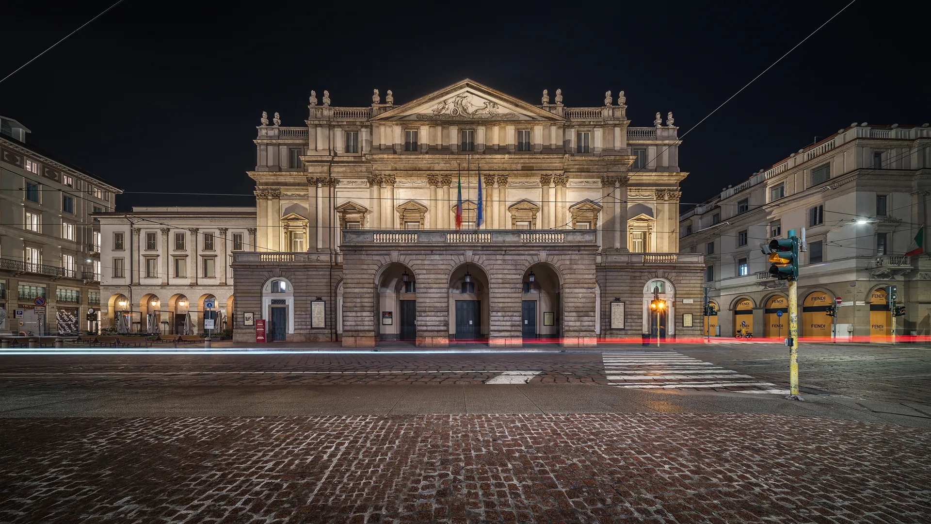 La Scala facade warmly lit at night, with people gathering