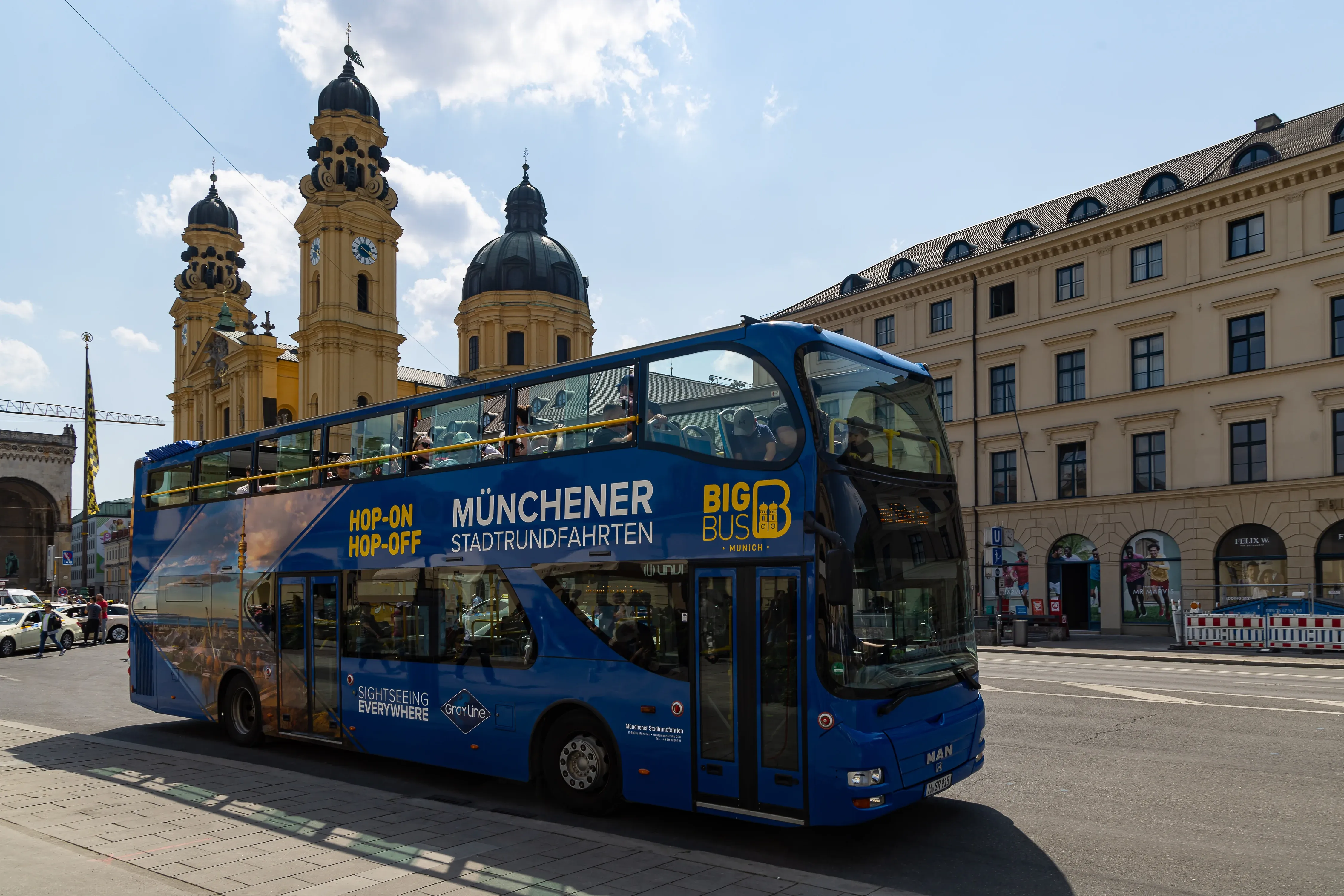 A red double-decker sightseeing bus driving through Munich streets