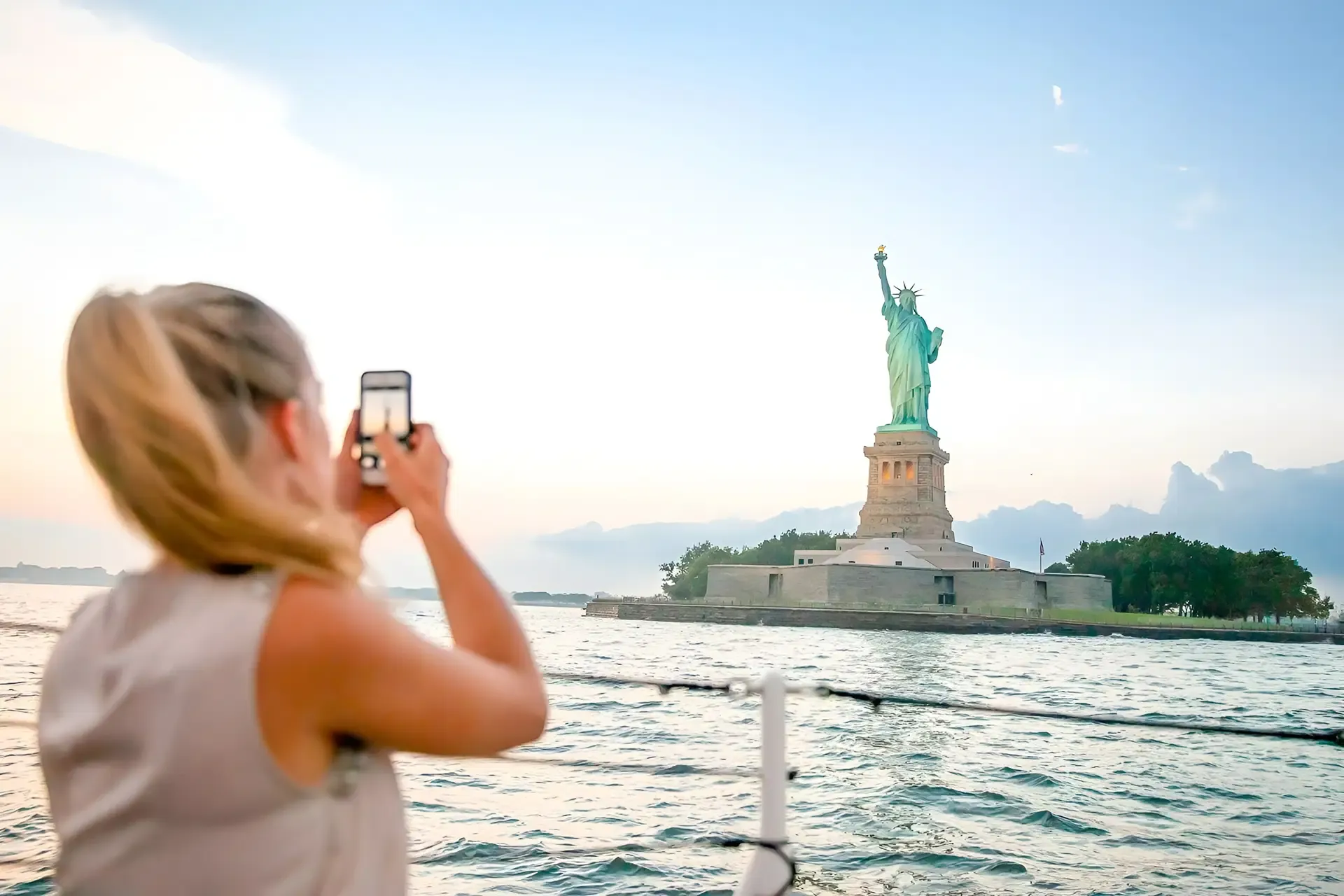 Visitor taking a photo of the Statue of Liberty from a cruise