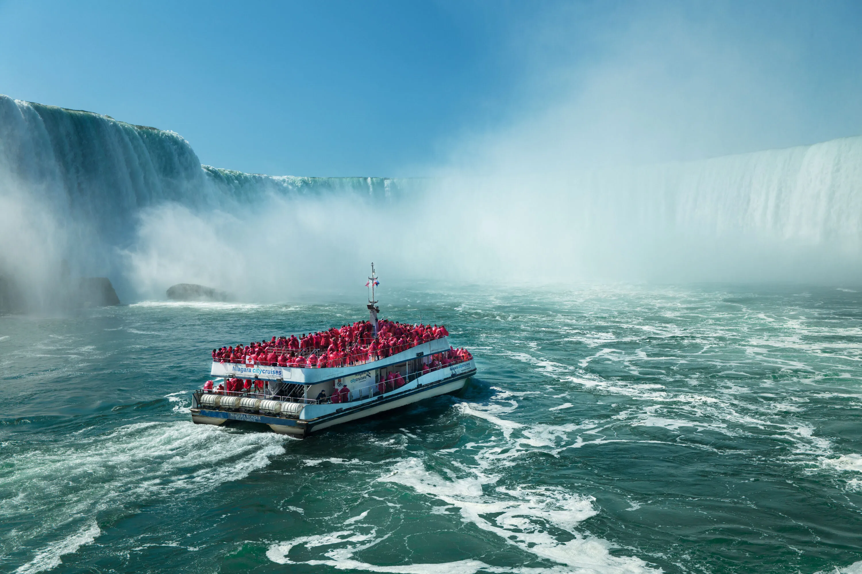Sightseeing boat full of visitors in red ponchos near the Falls
