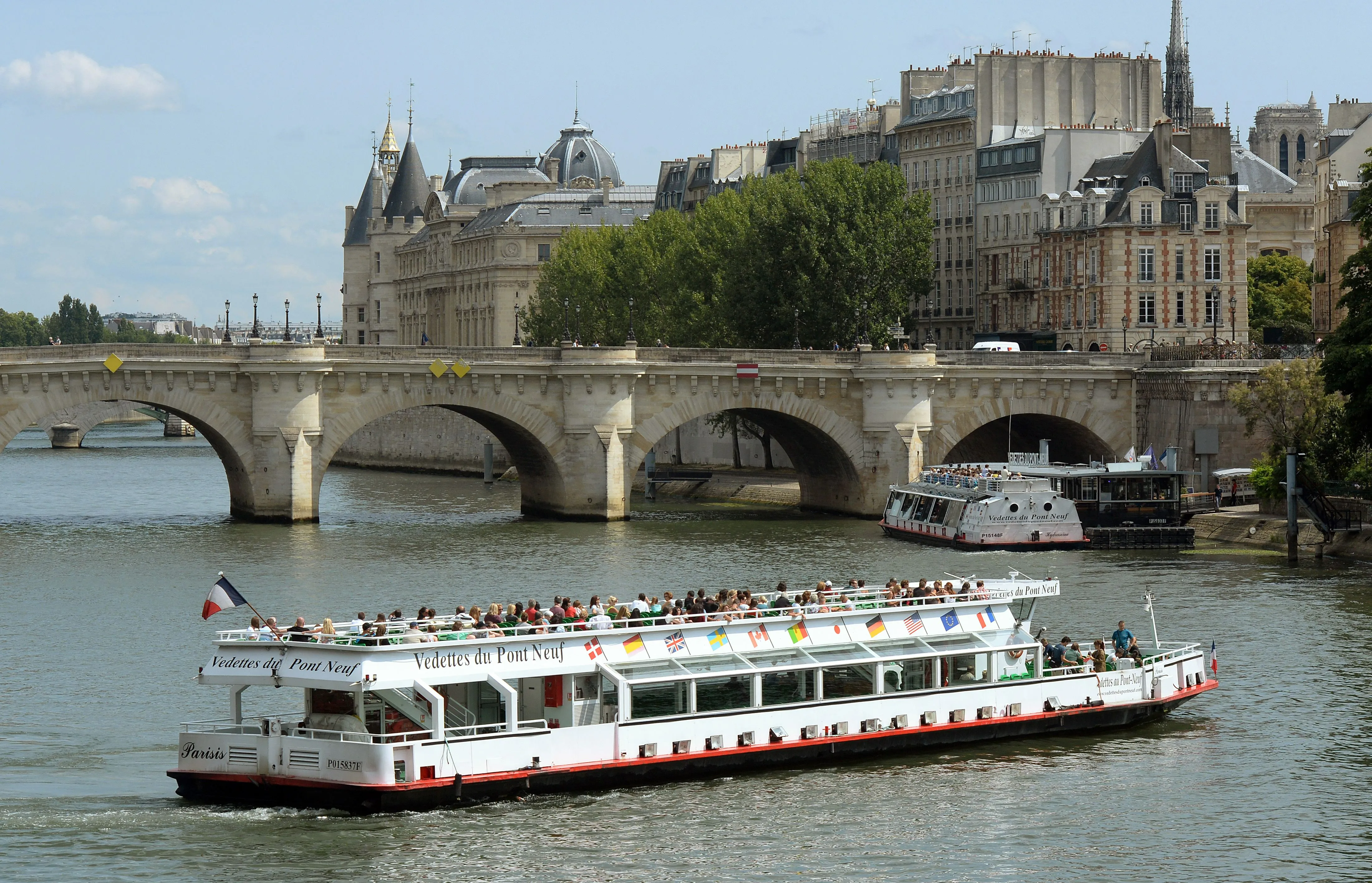 Three different Seine cruise boats passing historic bridges in Paris