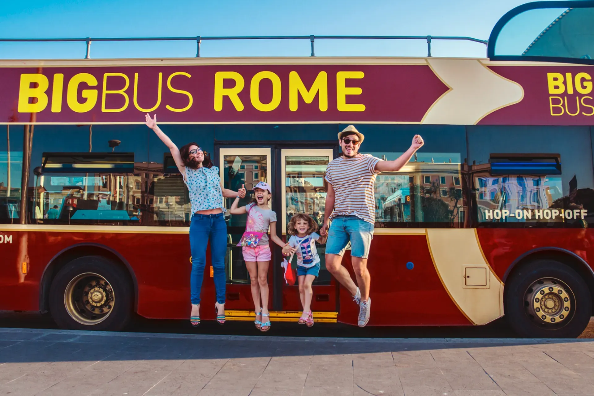 A happy family smiling on the top deck of a sightseeing bus