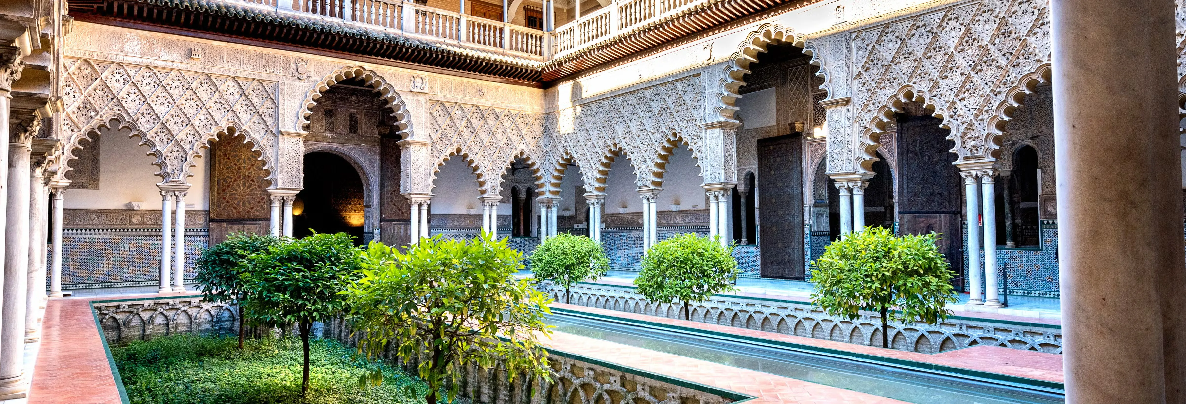 Decorative stucco and tilework framing arches in an Alcázar courtyard